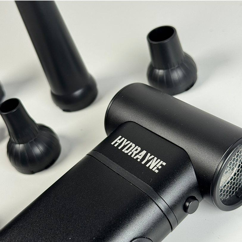 Black hair dryer with multiple nozzle attachments on a white background.