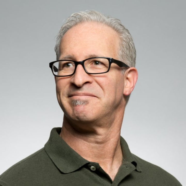 Man with glasses and gray hair looking to the side.