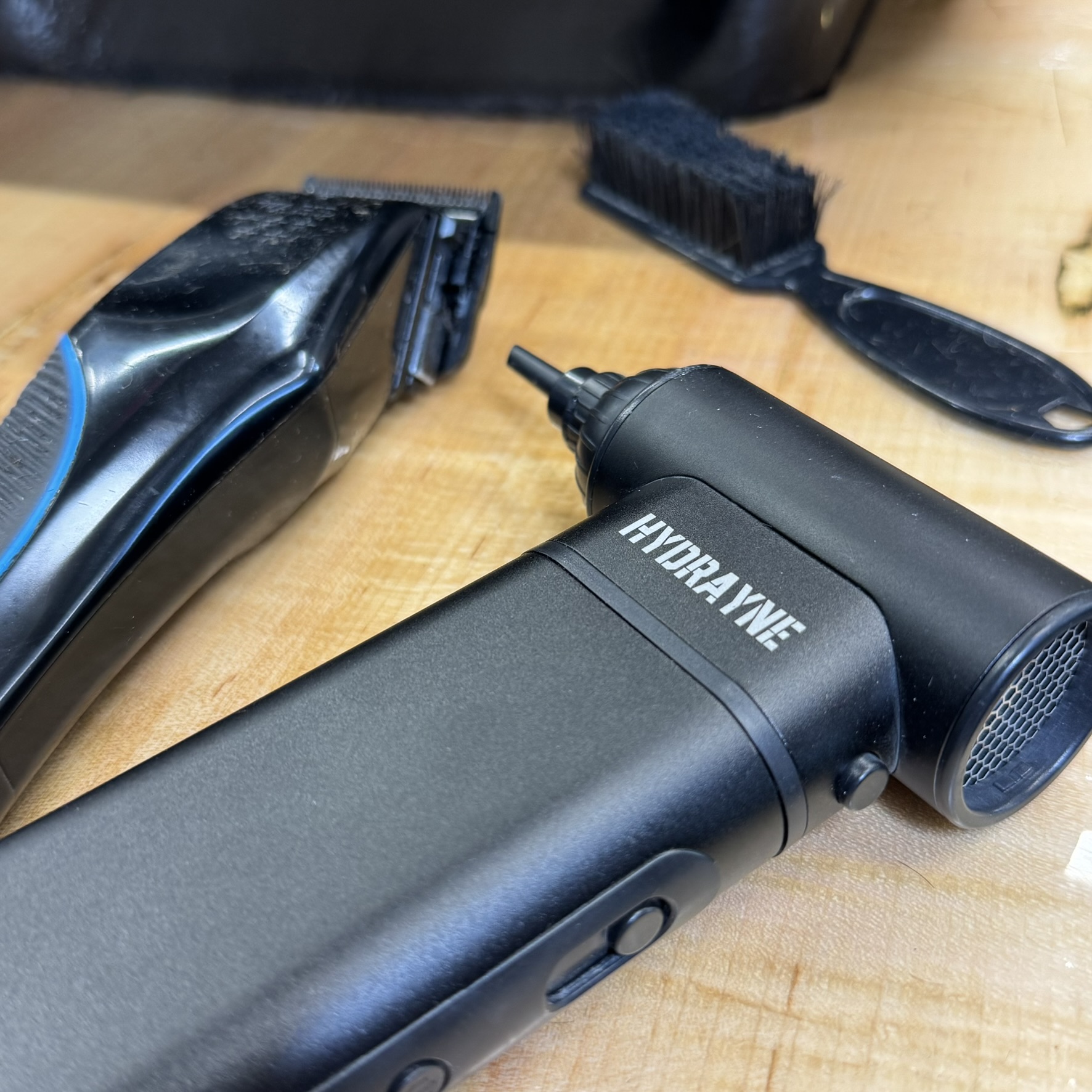 Close-up of grooming tools on a wooden surface, including a trimmer and a small brush.