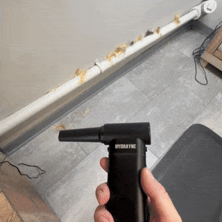 Person using a handheld device to clean dust from a pipe.
