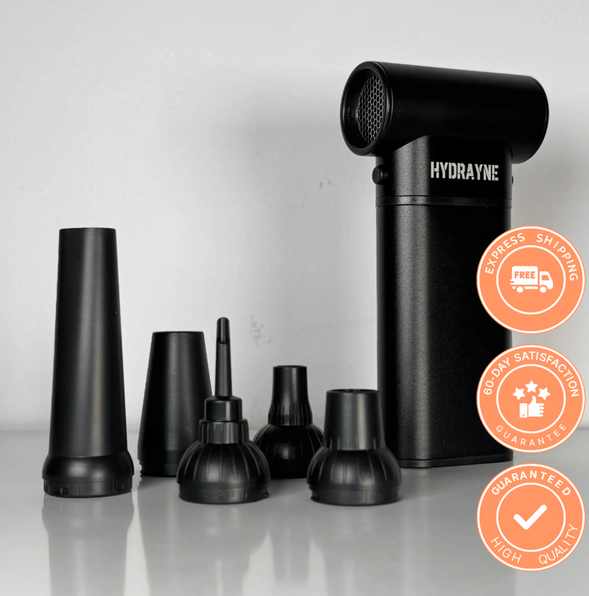 Black handheld device with multiple nozzle attachments on a grey surface.