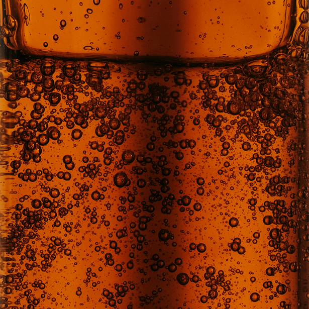 Close-up of bubbles in a dark amber liquid.