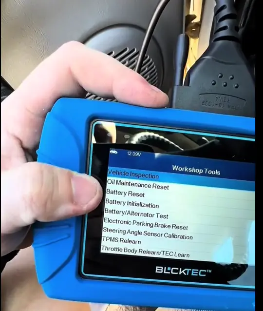 Hand holding a diagnostic tool displaying vehicle inspection options.