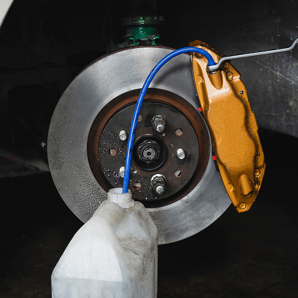 Car brake disc and caliper with fluid container attached.