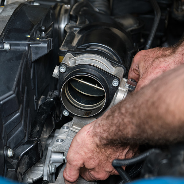 Hands working on a car engine component.