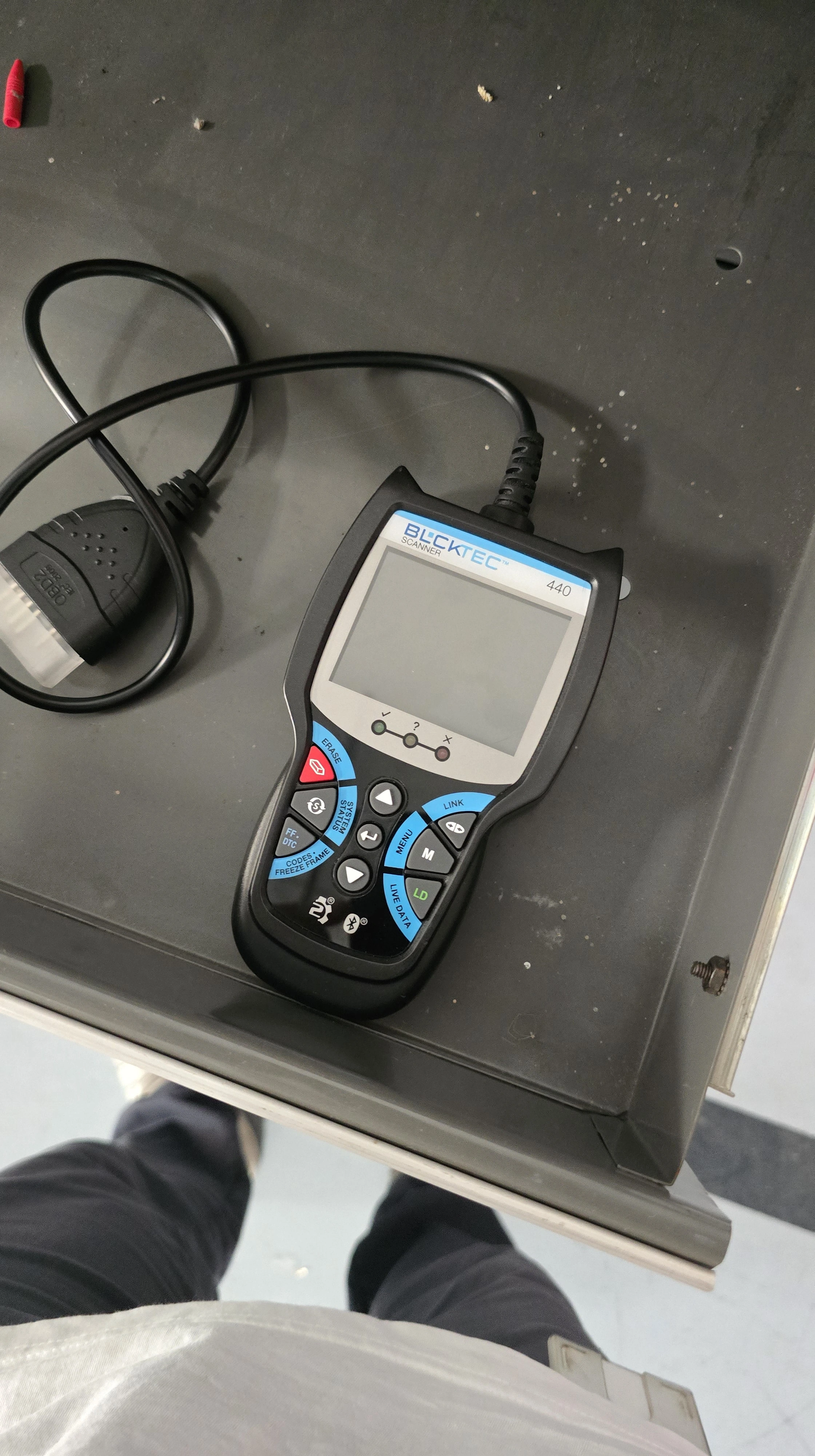 A diagnostic scanner with buttons and a screen on a gray surface.