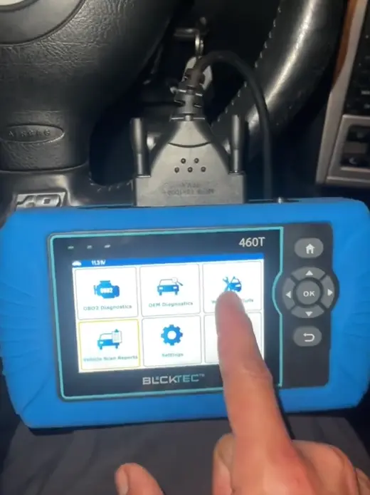 Person using a diagnostic tool on a car's steering wheel.