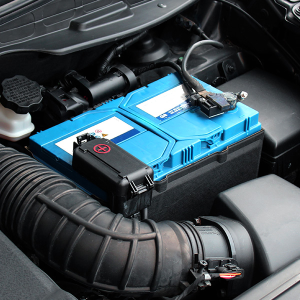 Car engine compartment with a blue battery and various components.