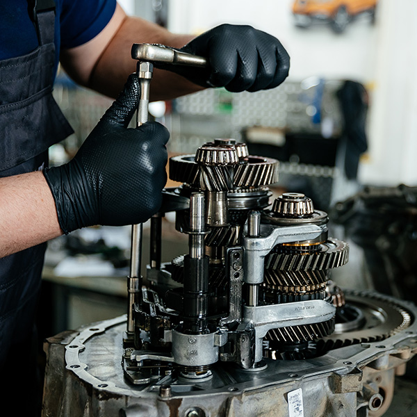 Mechanic working on a gearbox with tools in a workshop.