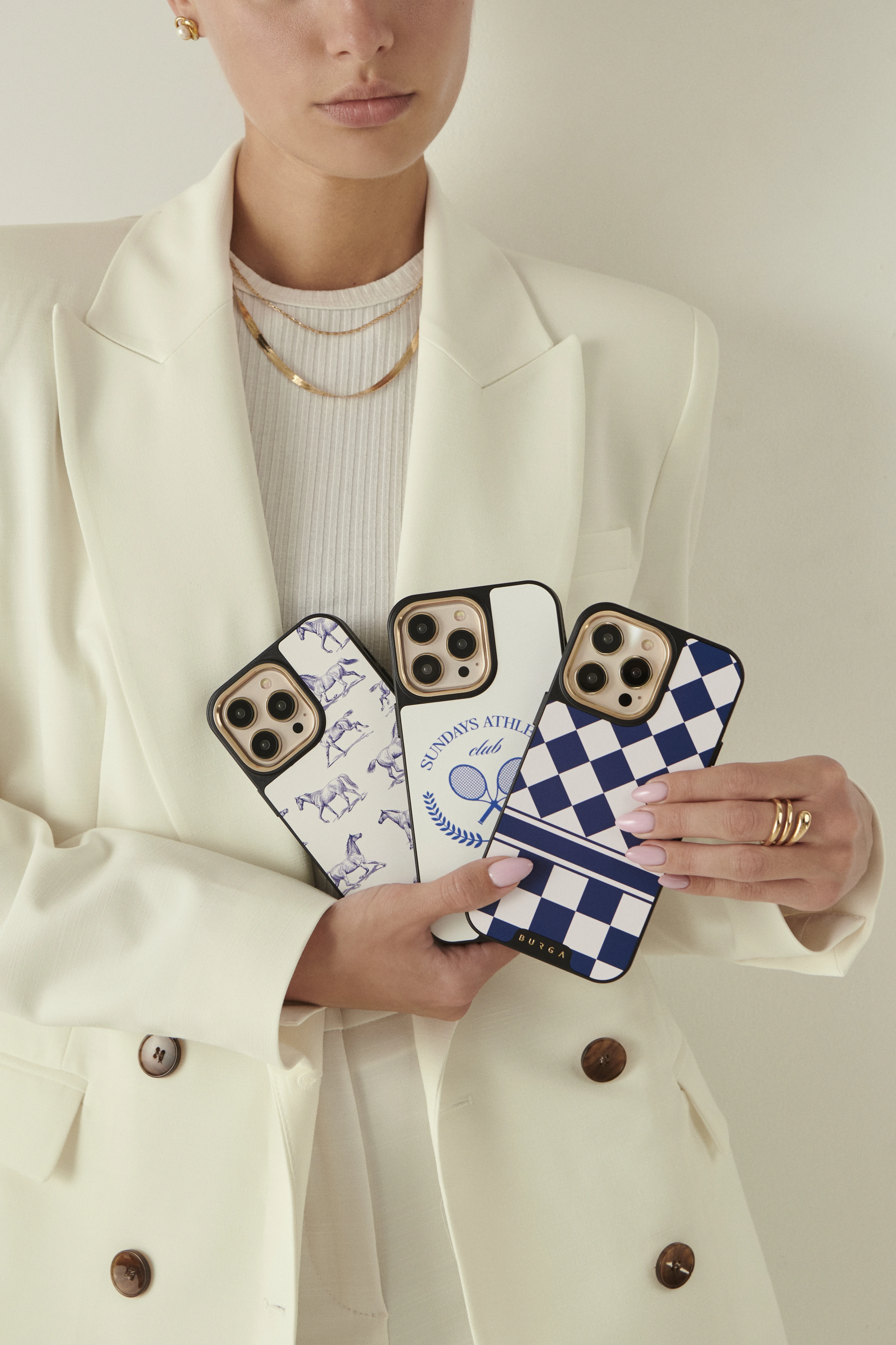 Two hands holding phones with colorful, food-themed cases by the sea.