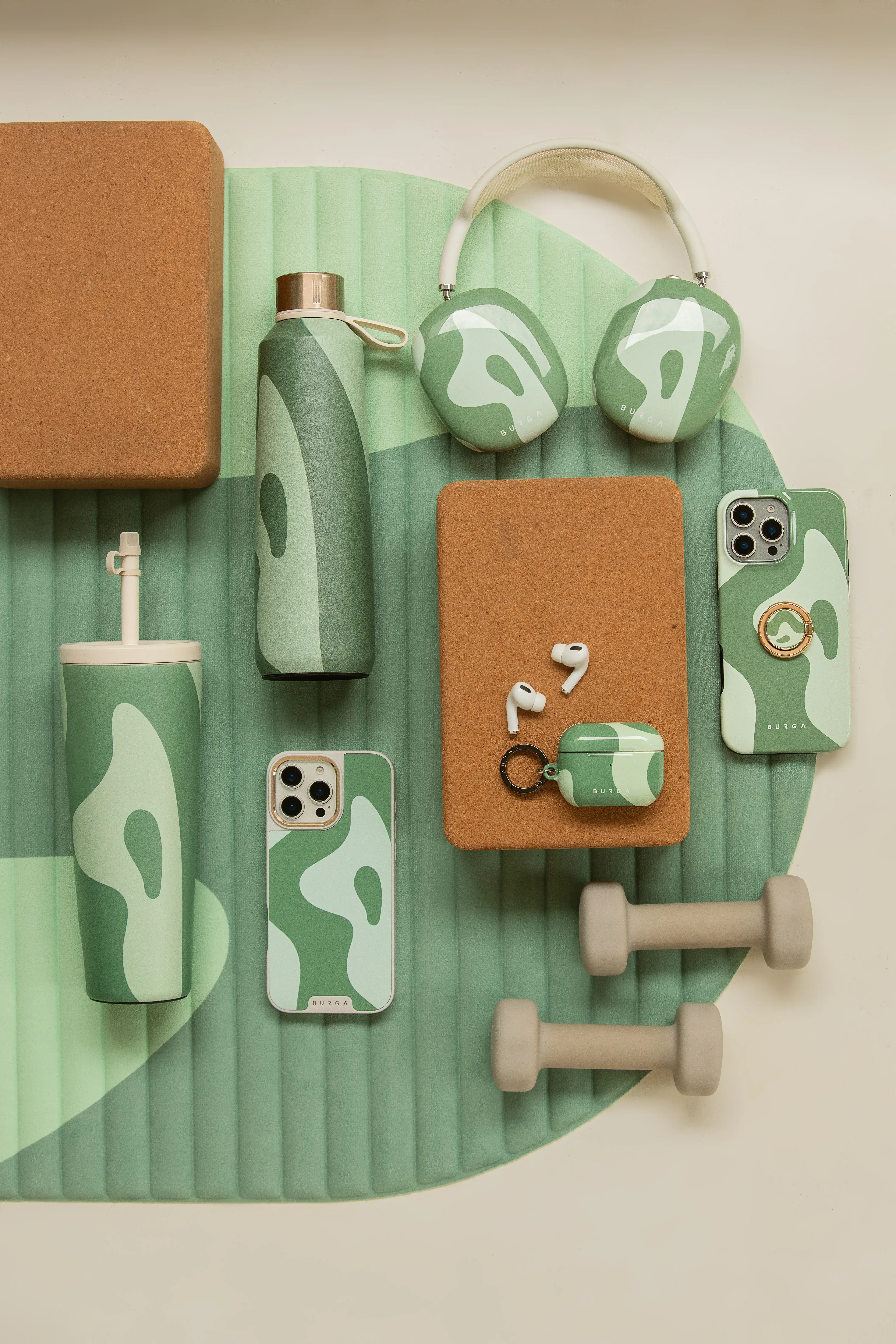 Green and beige fitness and tech accessories on a yoga mat.