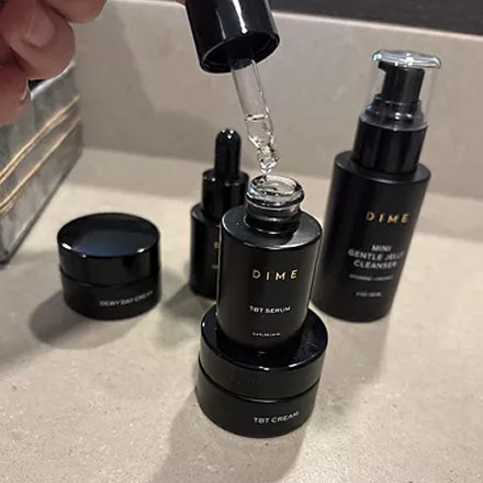 Skincare products with black packaging, including serum, cream, and cleanser, on a countertop.