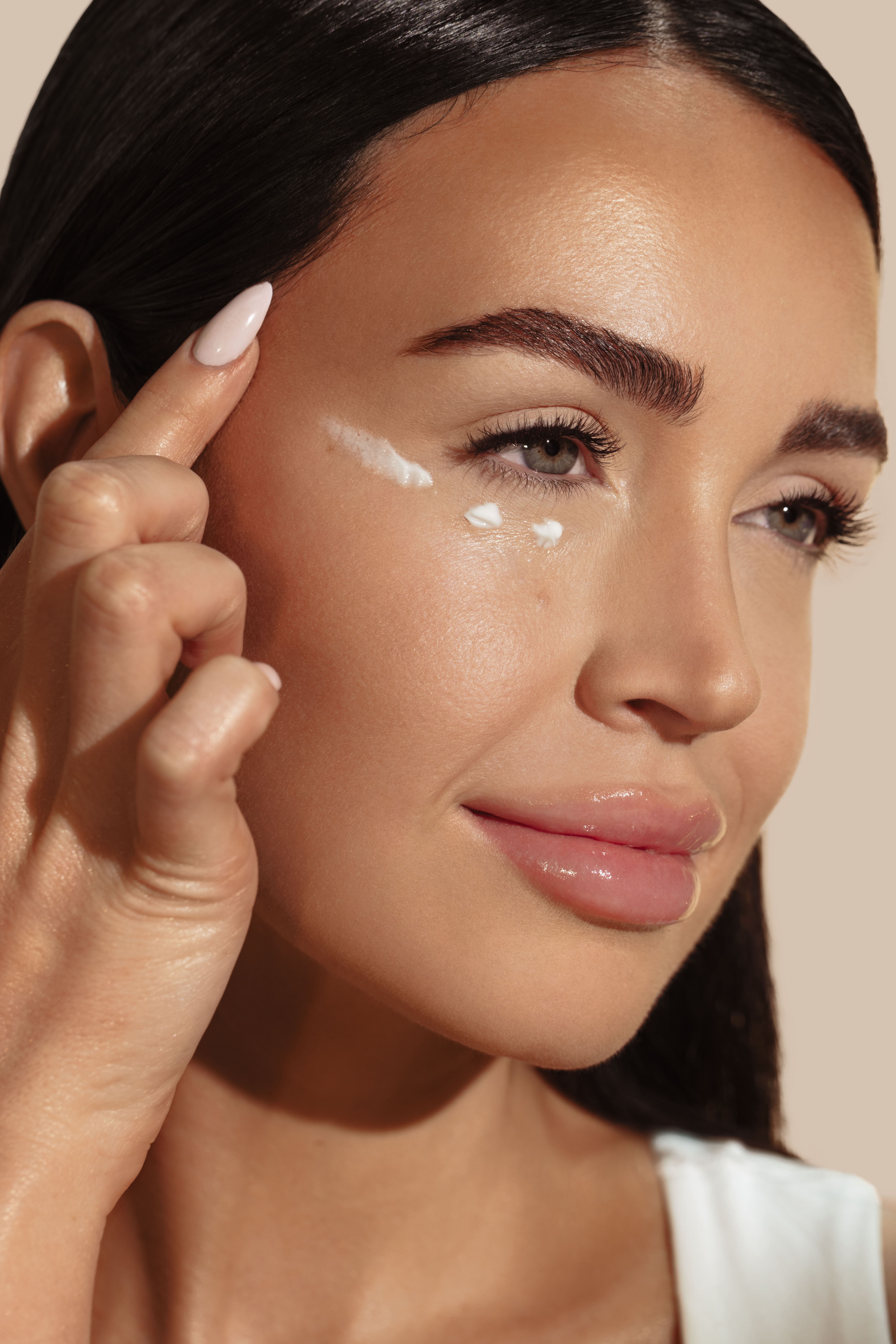 Close-up of a woman applying cream under her eye.