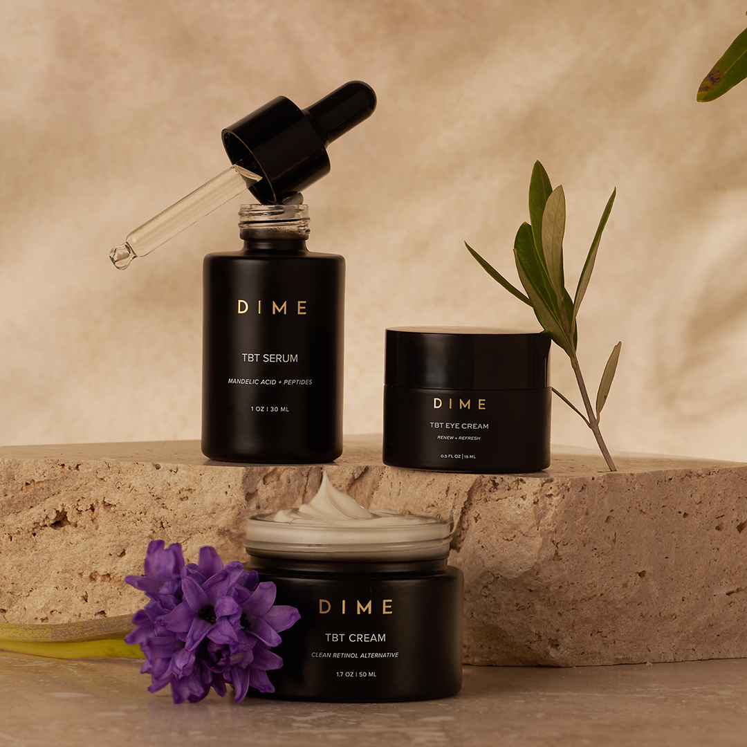 Four black bottles of Dime Nourishing Cleansing Oil on a beige background.