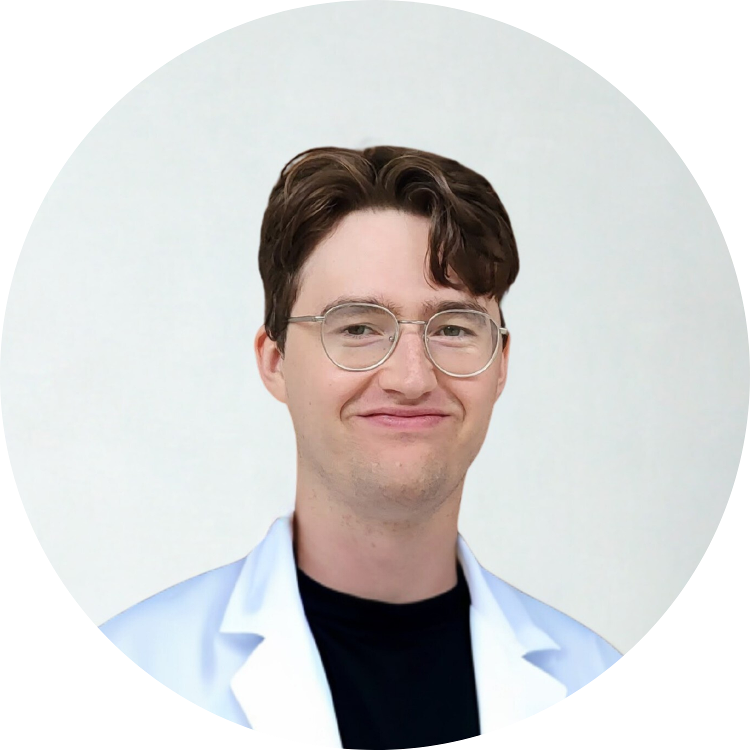 Person with glasses wearing a white coat and black shirt, smiling.