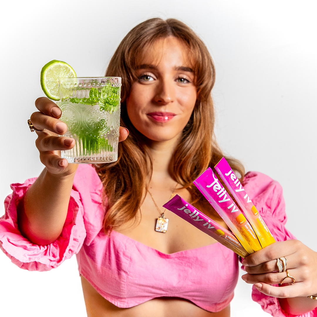 Woman in pink holding cocktail and colorful Jelly sticks.
