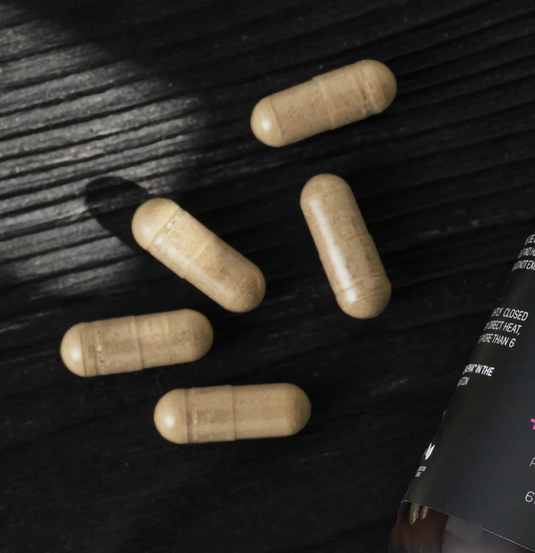 Five beige capsules on a dark wooden surface.