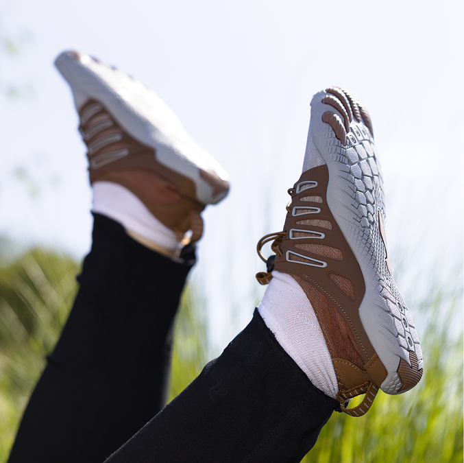 Person lying in grass with brown minimalist shoes and white socks.