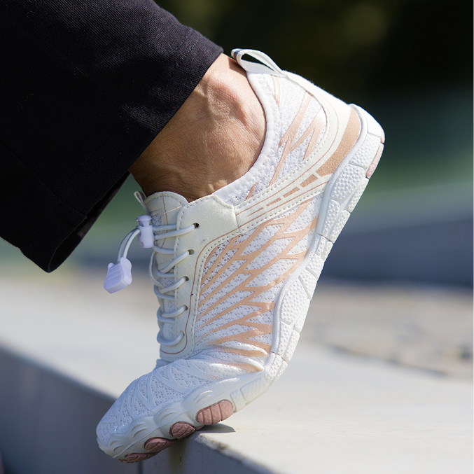 Close-up of a foot wearing a white sneaker with intricate design.