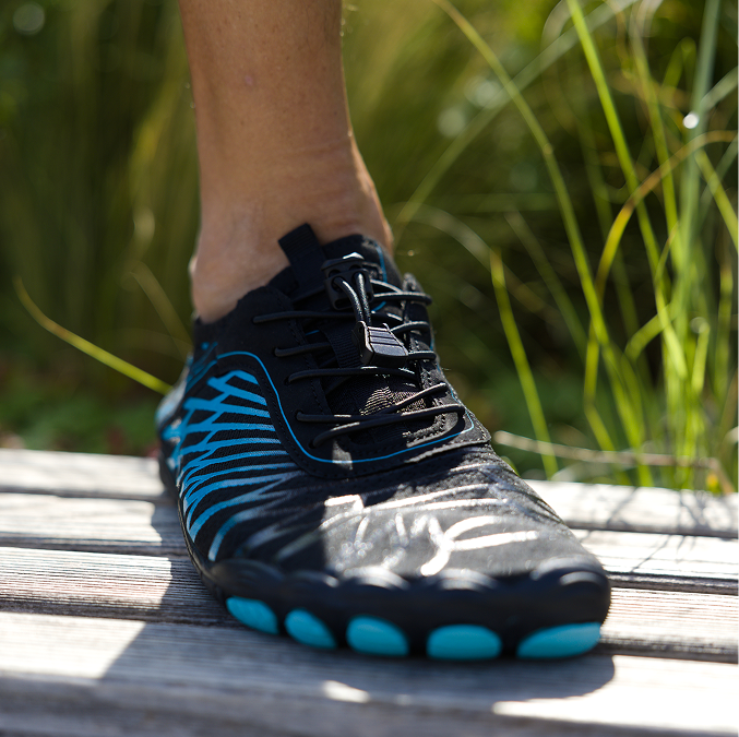 Black and blue shoe on a wooden surface with grass in the background.