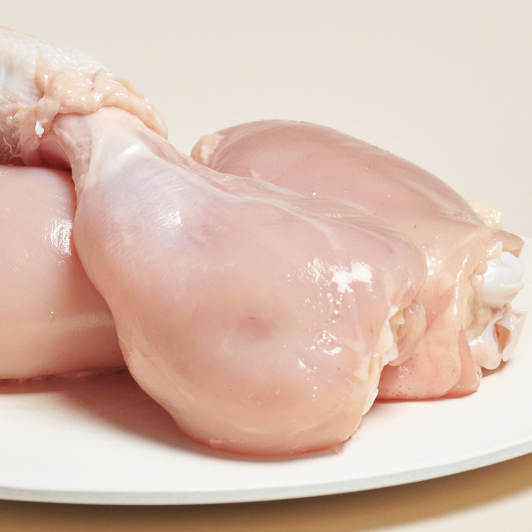Raw chicken drumsticks on a white plate.