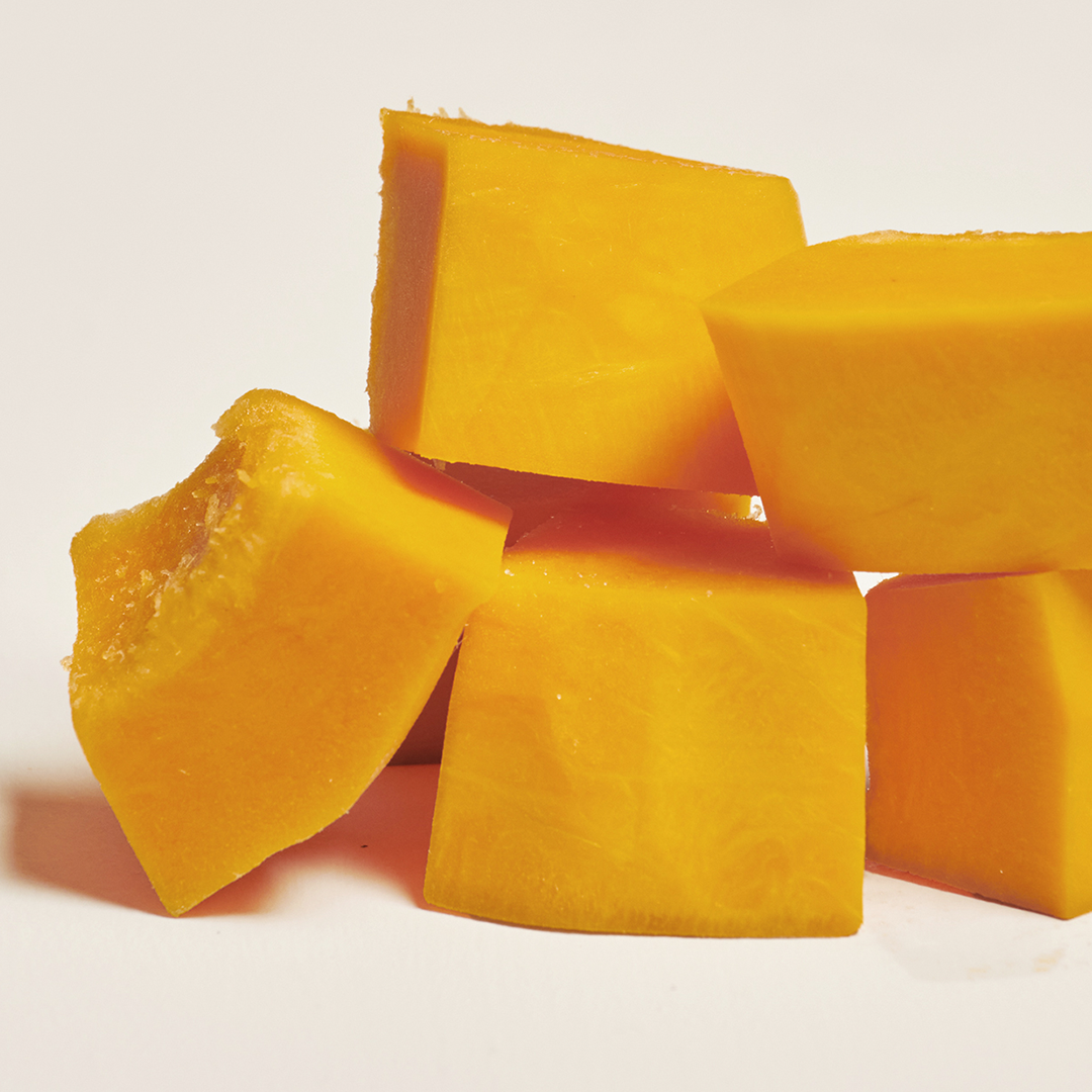 Cubes of ripe mango stacked on a white surface.