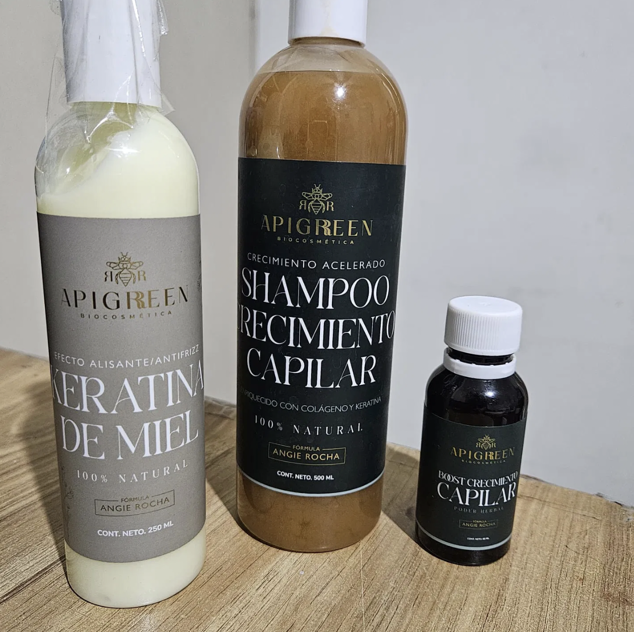Hair care products: keratin de miel, shampoo, and growth boost by Apigreen on a wooden surface.