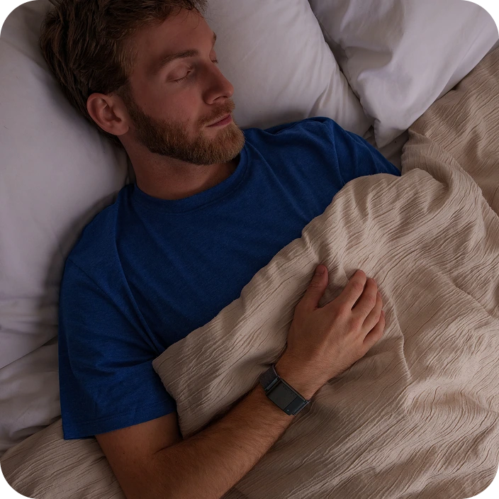 Man sleeping in bed, wearing a blue shirt and a smartwatch.