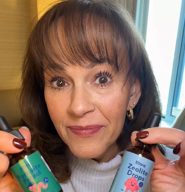 Person holding bottles labeled Parasite Patrol and Zeolite Drops.