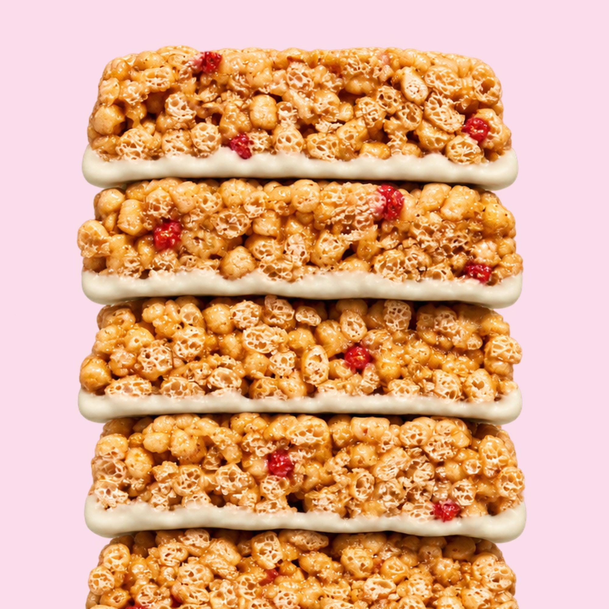 A Mezcla Frosted Strawberry protein bar with unwrapped bars, fresh strawberries, and white chocolate on a pink background.