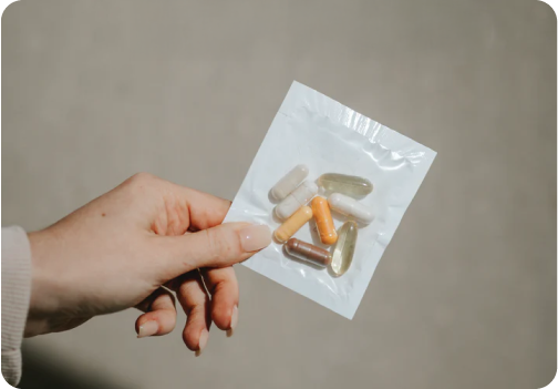 Hand holding a small packet of assorted capsules.