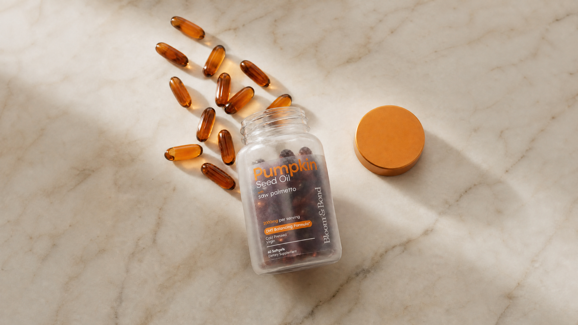 An open bottle of Pumpkin Seed Oil softgels with several capsules spilled out on a marble surface.