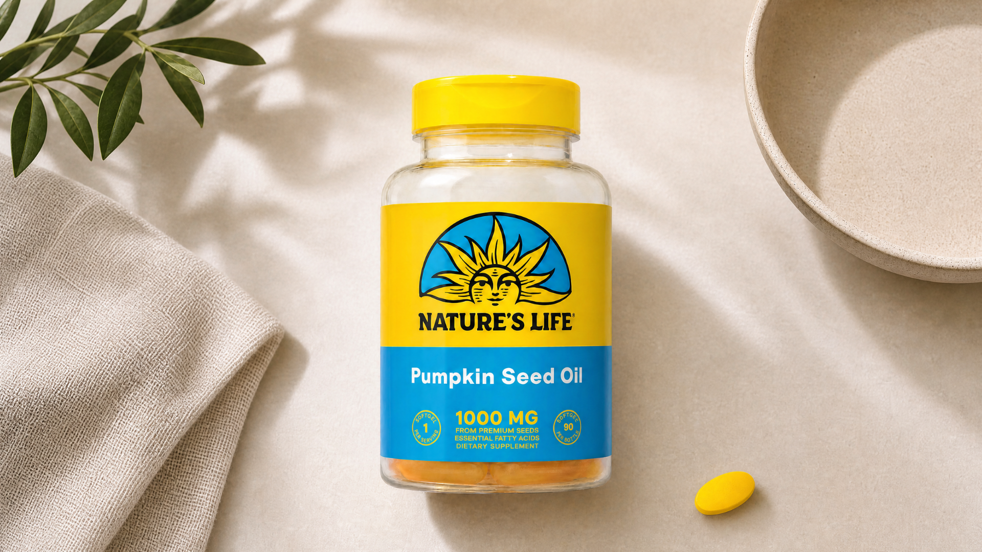 A bottle of Nature's Life Pumpkin Seed Oil on a surface with a cloth, plant, and bowl.