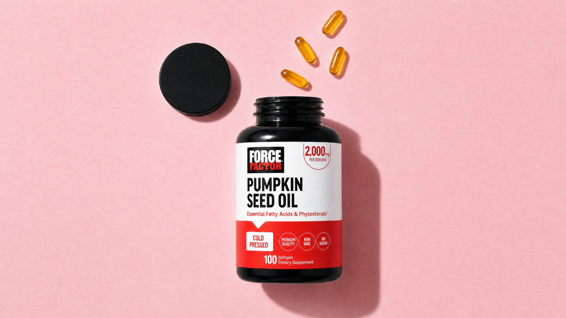A bottle of Force Factor Pumpkin Seed Oil on a pink background, with its cap off and softgels spilled out.