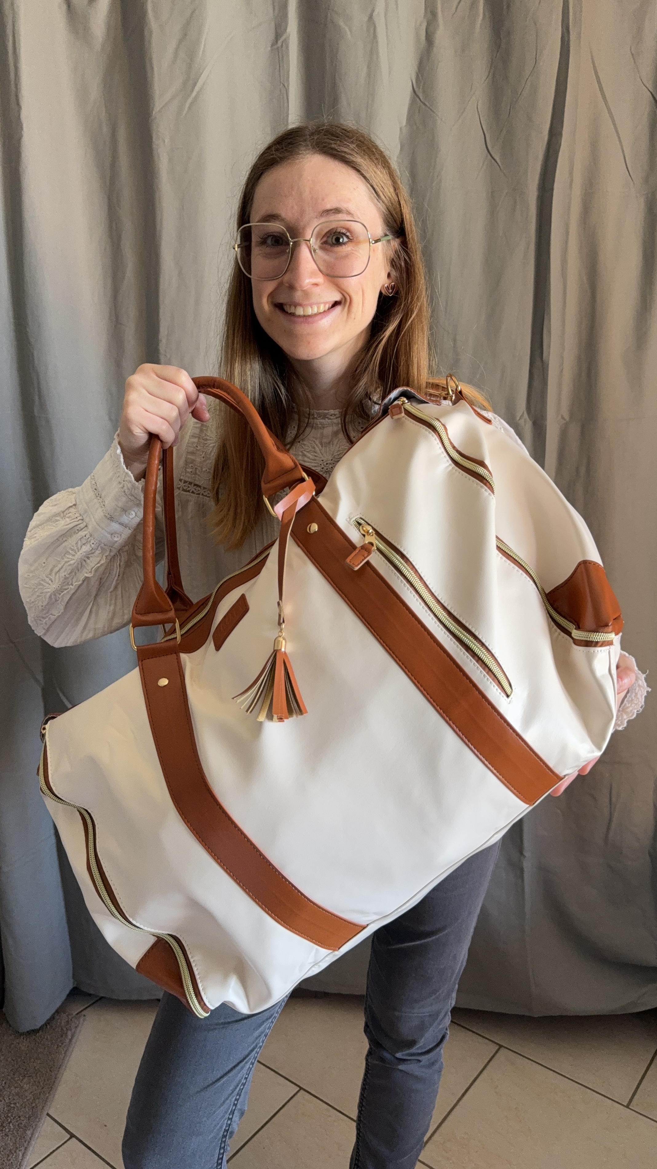 Person holding a large white and brown bag, smiling.