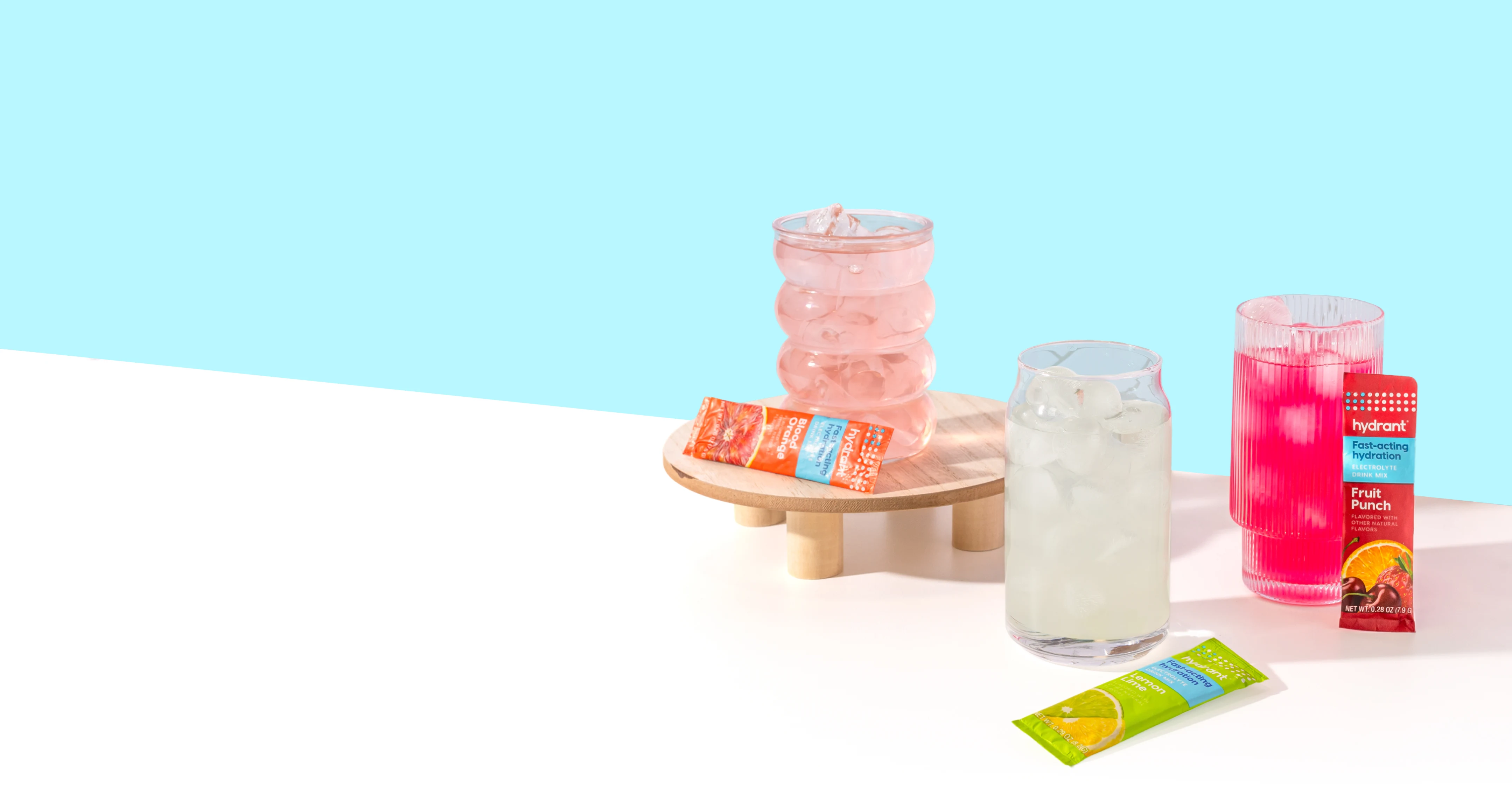 Three colorful iced drinks in glasses are displayed with their corresponding Hydrant brand flavor packets.
