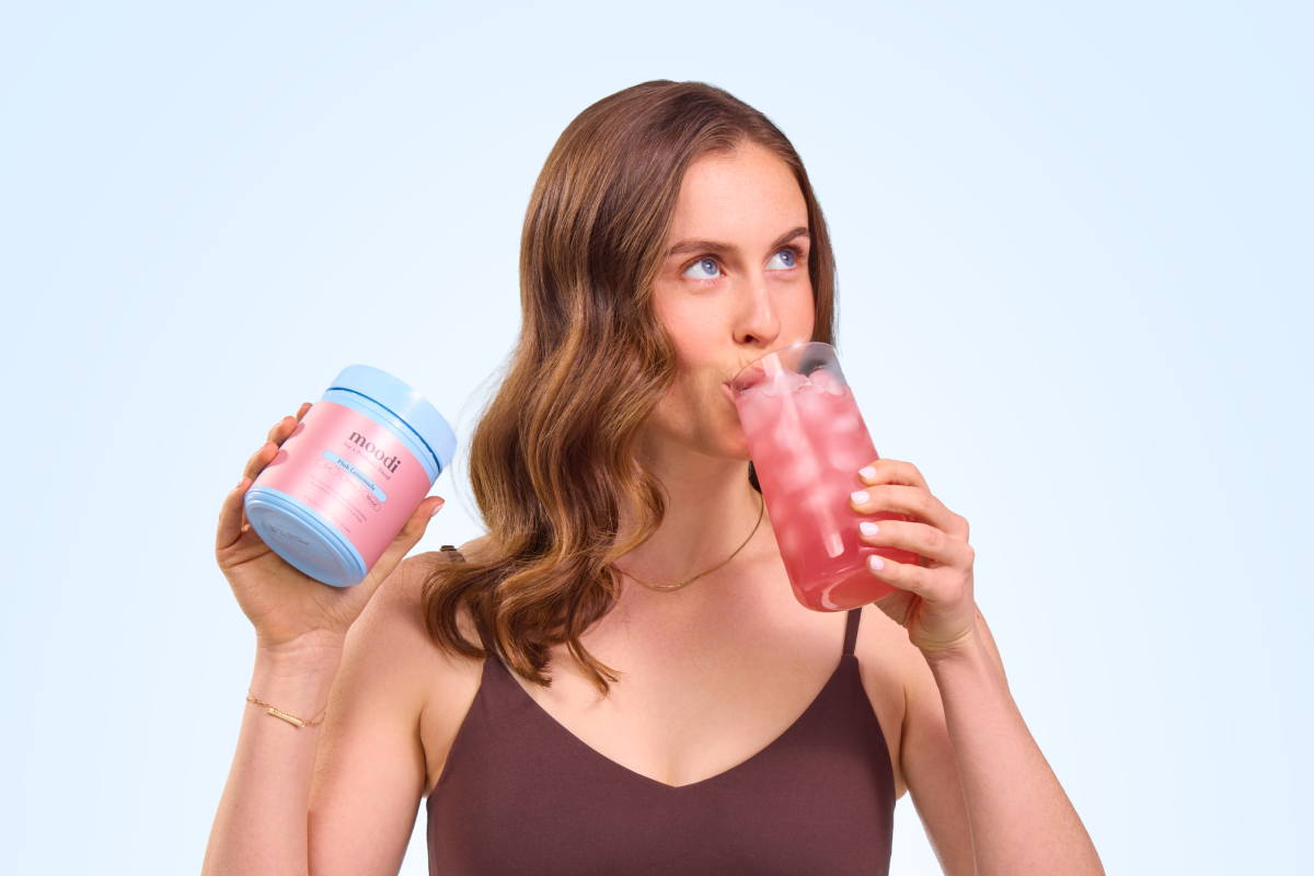 Person holding a container and drinking a pink beverage.