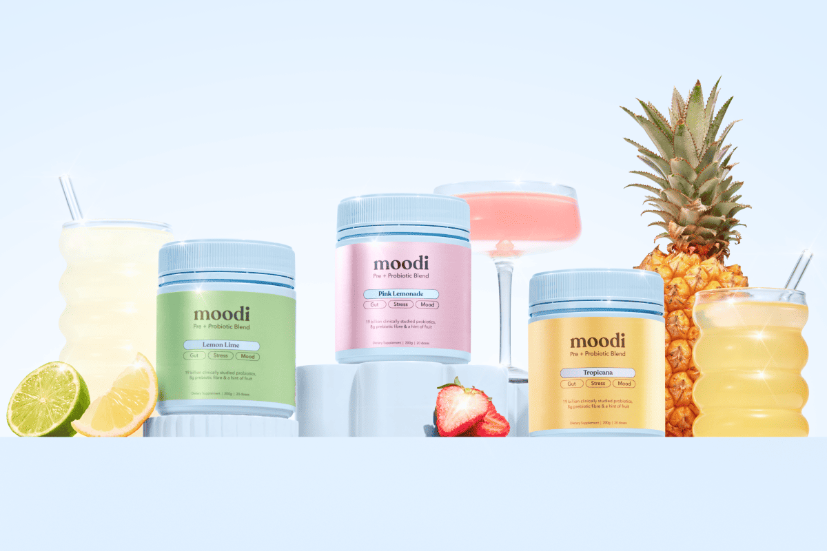 Three jars of Moodi Pre + Probiotic Blend, styled with fruits and drinks matching their flavors.