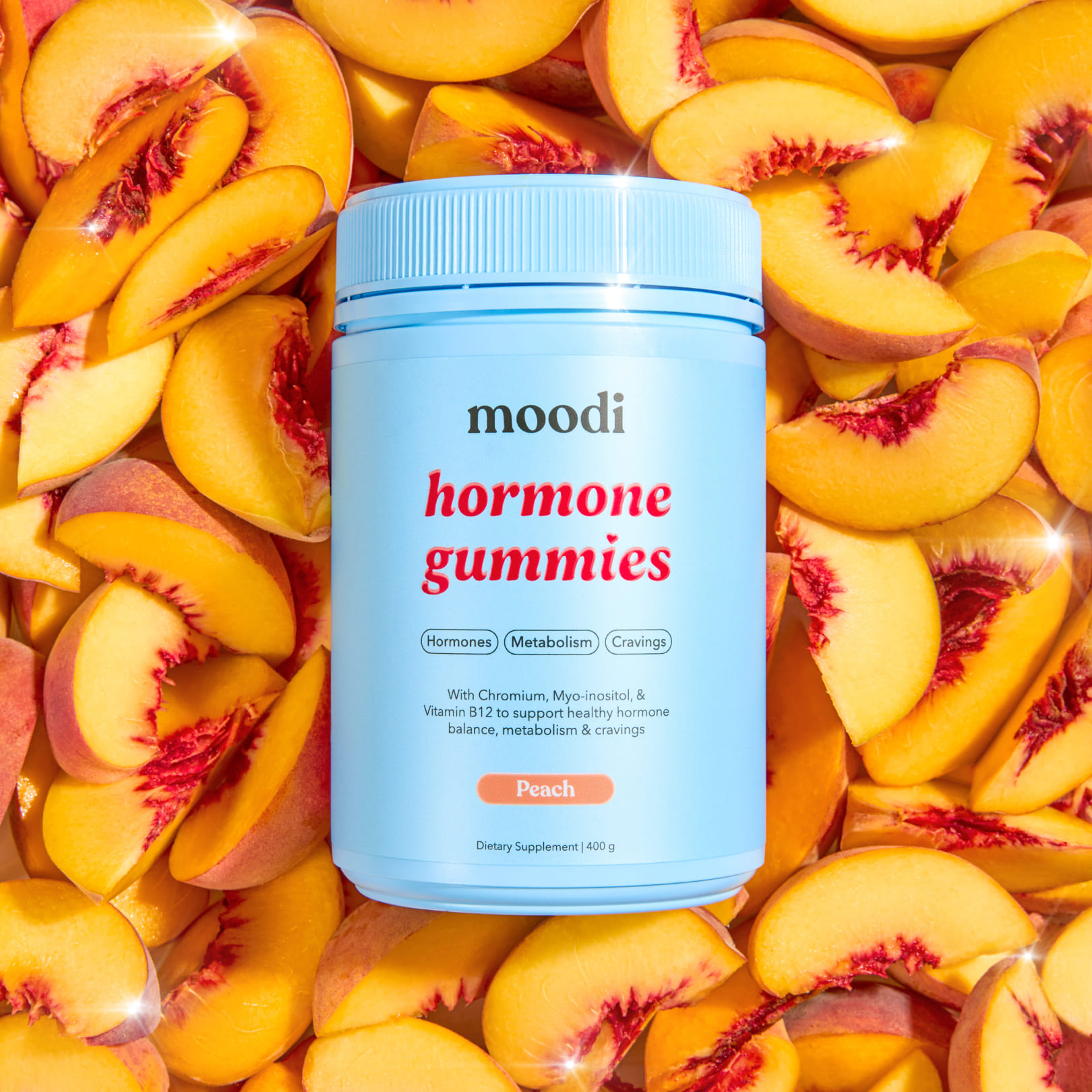 A light blue bottle of Moodi Hormone Gummies sits on a bed of freshly sliced peaches.
