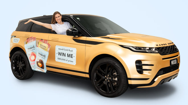 A woman smiles from the driver's seat of a gold Range Rover with 'moodi Gold Rush' contest branding.