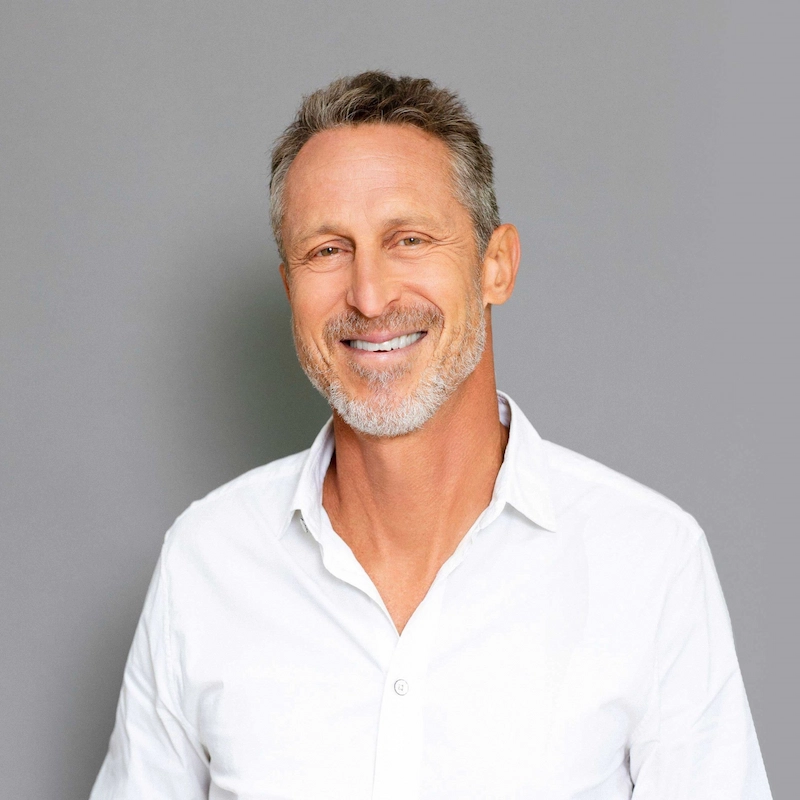 Smiling man in a white shirt against a gray background.
