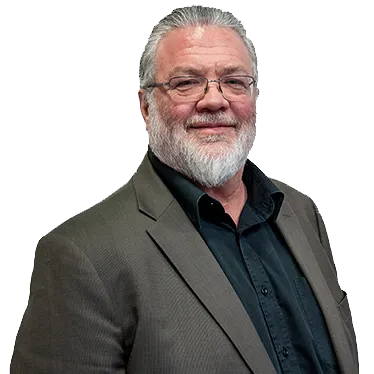 A bearded man in a suit jacket and glasses, smiling.