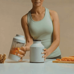 Person assembling a blender with orange ingredients inside.