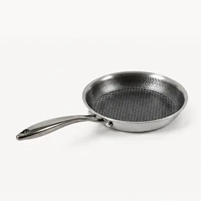 A stainless steel frying pan with a honeycomb pattern on its interior surface, against a white background.