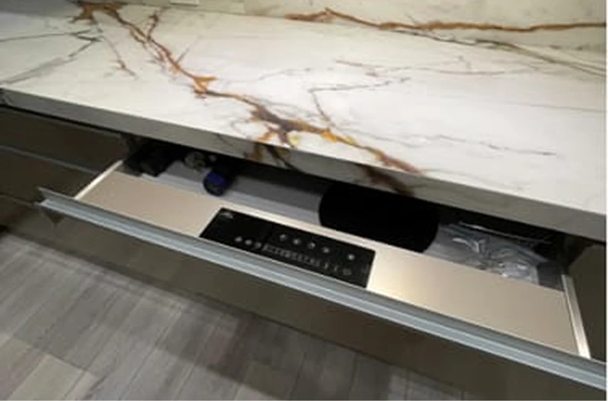A control panel built into an open drawer under a white and gold marbled countertop.
