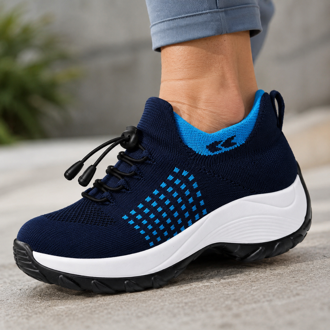 A close-up of a person's foot wearing a blue knit sneaker with a white sole and toggle laces.