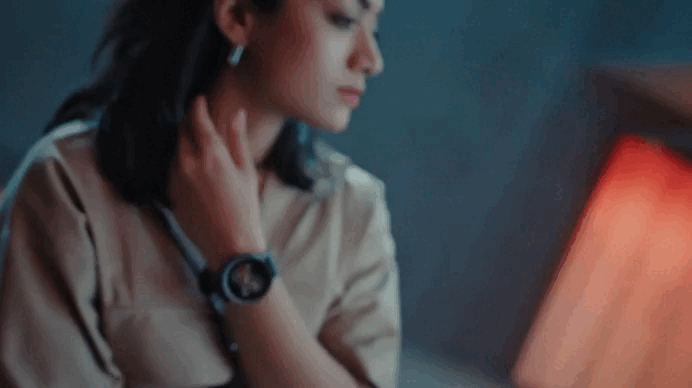 Woman with dark hair wearing a smartwatch, looking down.