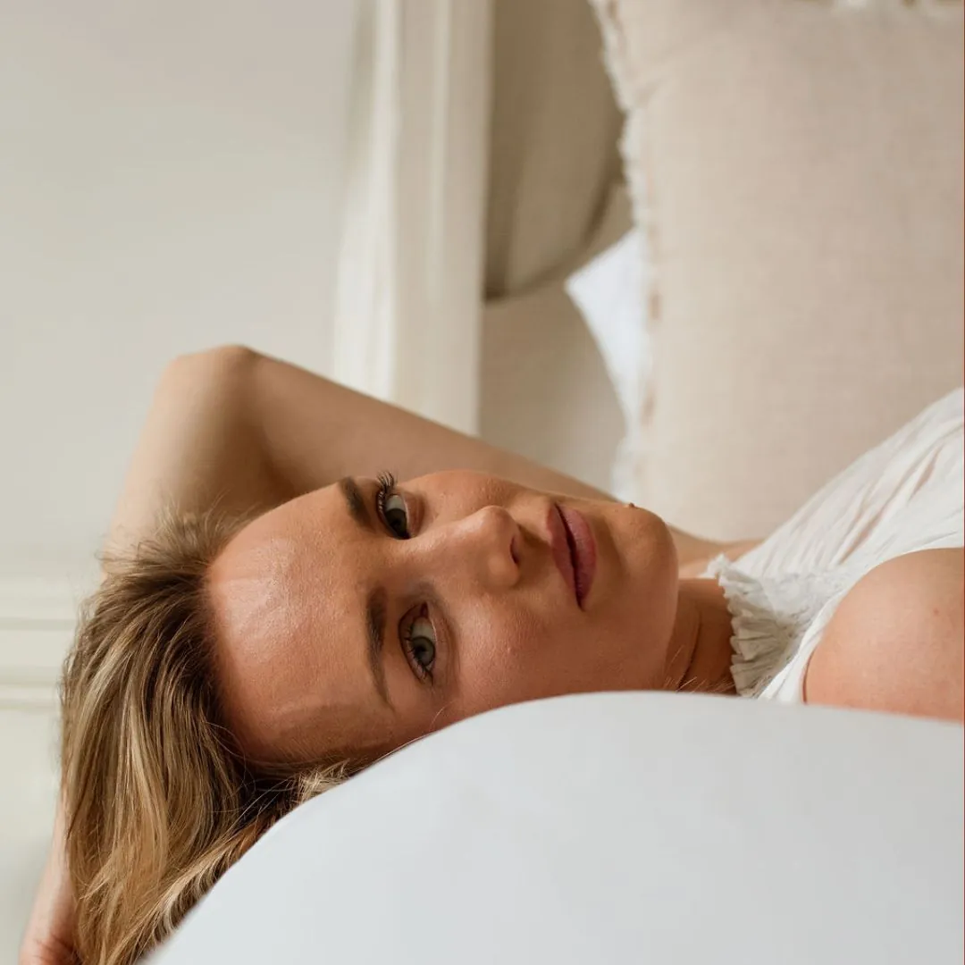 Person lying on a white pillow, looking towards the camera.