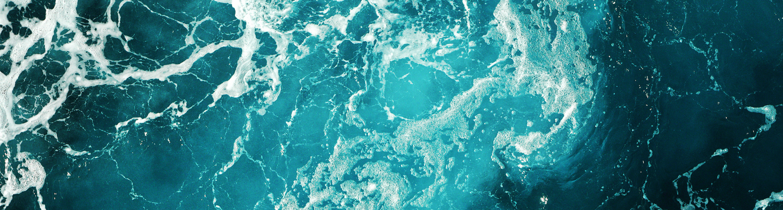 Aerial view of turquoise ocean waves and frothy white patterns.