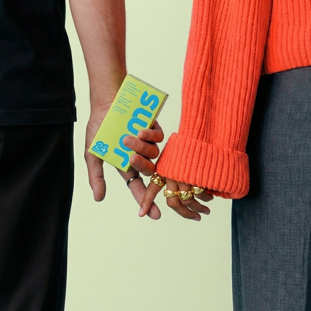 Two people smiling, one holding a box labeled 'gems', in a casual setting.